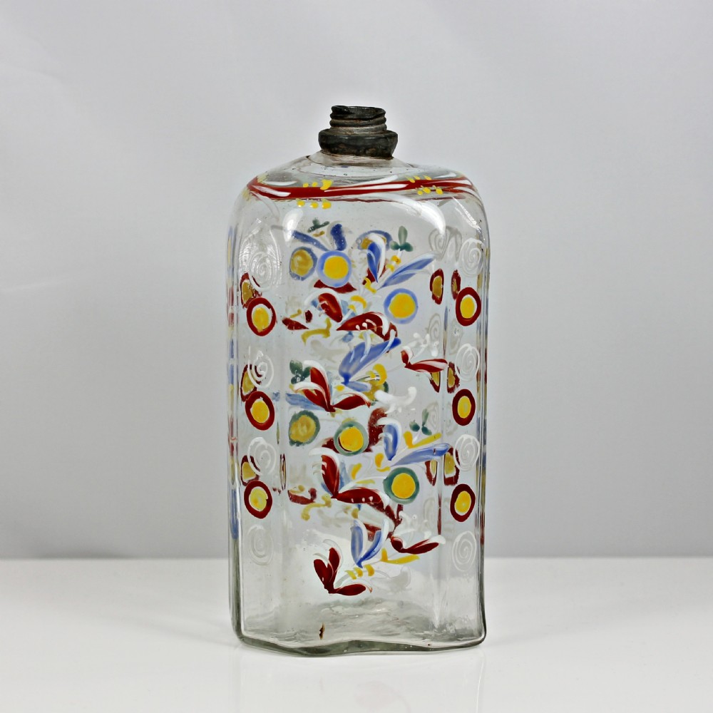 An 18th-century rectangular clear glass schnapps flask featuring hand-painted polychrome floral enamelling and a threaded metal pewter cap.