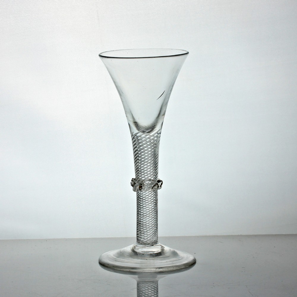 A clear 18th-century Georgian wine glass featuring a flared trumpet bowl, a multi-spiral air twist stem with a central vermicular collar, and a circular conical foot.