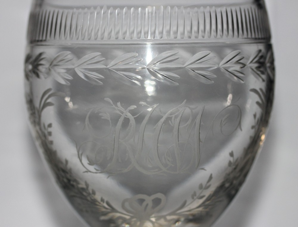 A clear Georgian glass goblet featuring an ovoid bowl with a wheel-engraved monogram and floral wreath above a short plain stem and circular foot. View II