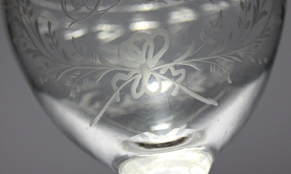 A clear Georgian glass goblet featuring an ovoid bowl with a wheel-engraved monogram and floral wreath above a short plain stem and circular foot. View III
