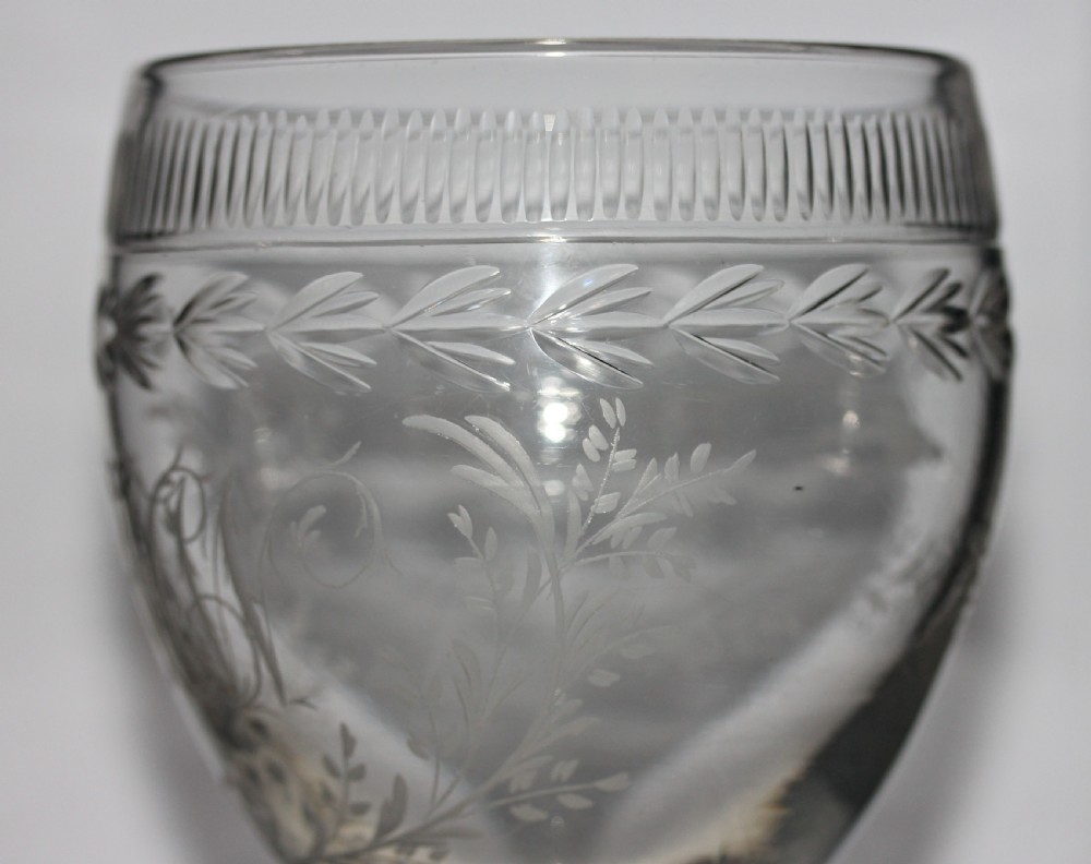 A clear Georgian glass goblet featuring an ovoid bowl with a wheel-engraved monogram and floral wreath above a short plain stem and circular foot. View IV