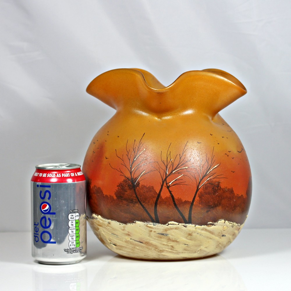A globular Art Nouveau glass vase featuring an amber to orange gradient body, a ruffled rim, and a painted winter landscape with bare trees and textured white snow along the base. View II