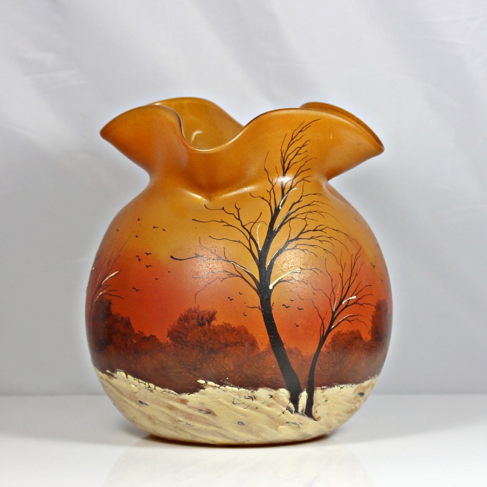 A globular Art Nouveau glass vase featuring an amber to orange gradient body, a ruffled rim, and a painted winter landscape with bare trees and textured white snow along the base. View III