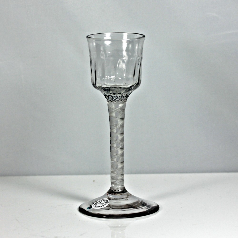 An 18th-century Georgian clear glass wine stemware with a flute-moulded ogee bowl, an opaque white twist stem, and a wide conical foot.