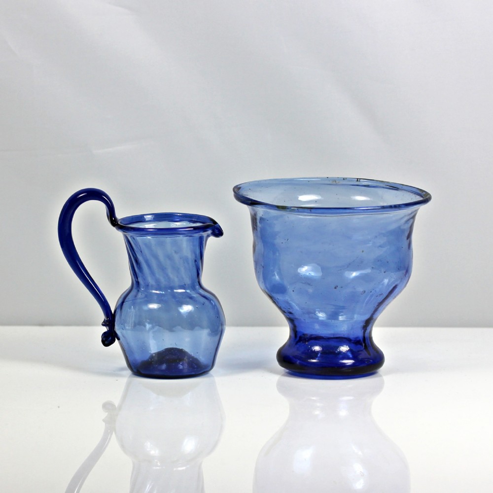 A two-piece set of Georgian blue hand-blown glass, comprising a small cream jug with a high loop handle and a matching rimmed sugar bowl.