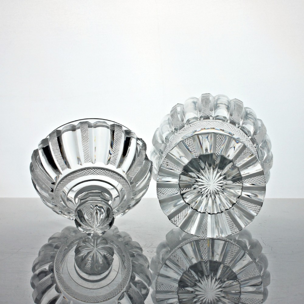 A clear cut glass preserve pot with a fitted lid and knopped finial resting on a matching scalloped glass saucer base. View IV