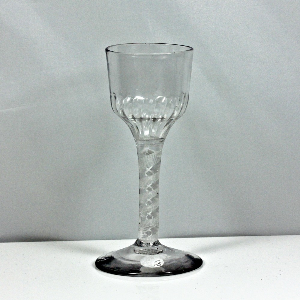 An 18th-century Georgian drinking glass featuring an opaque twist stem, a flute-moulded lower ogee bowl, and a circular conical foot.