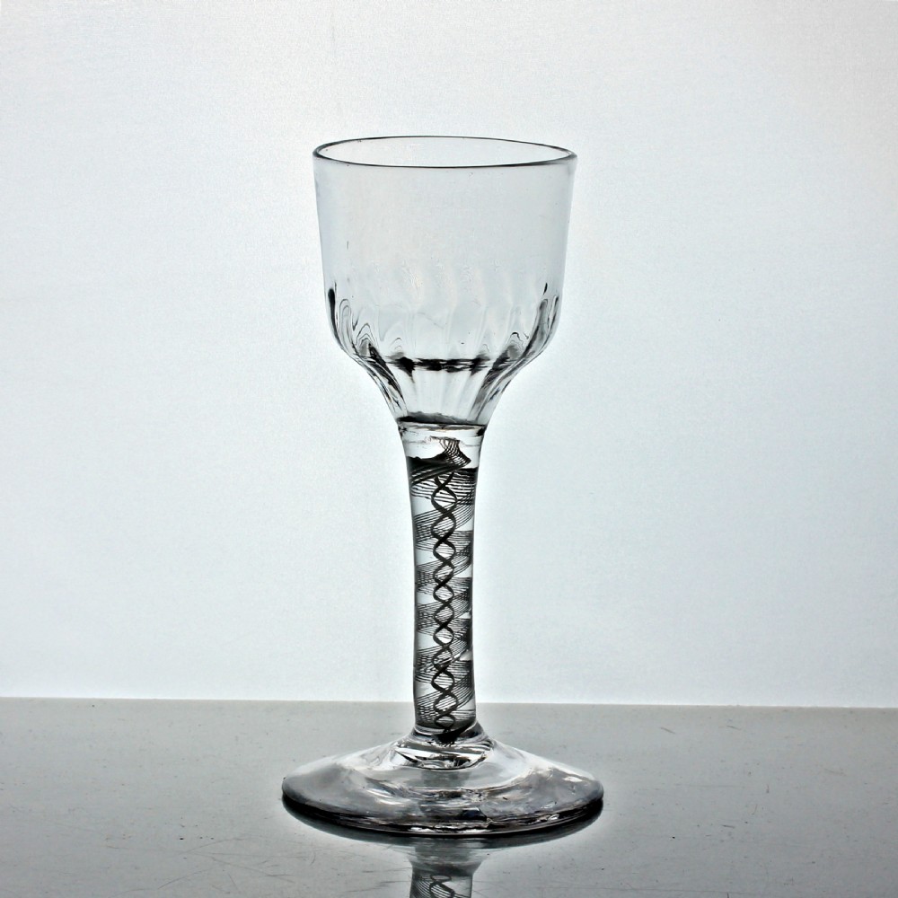 An 18th-century Georgian drinking glass featuring an opaque twist stem, a flute-moulded lower ogee bowl, and a circular conical foot. View II
