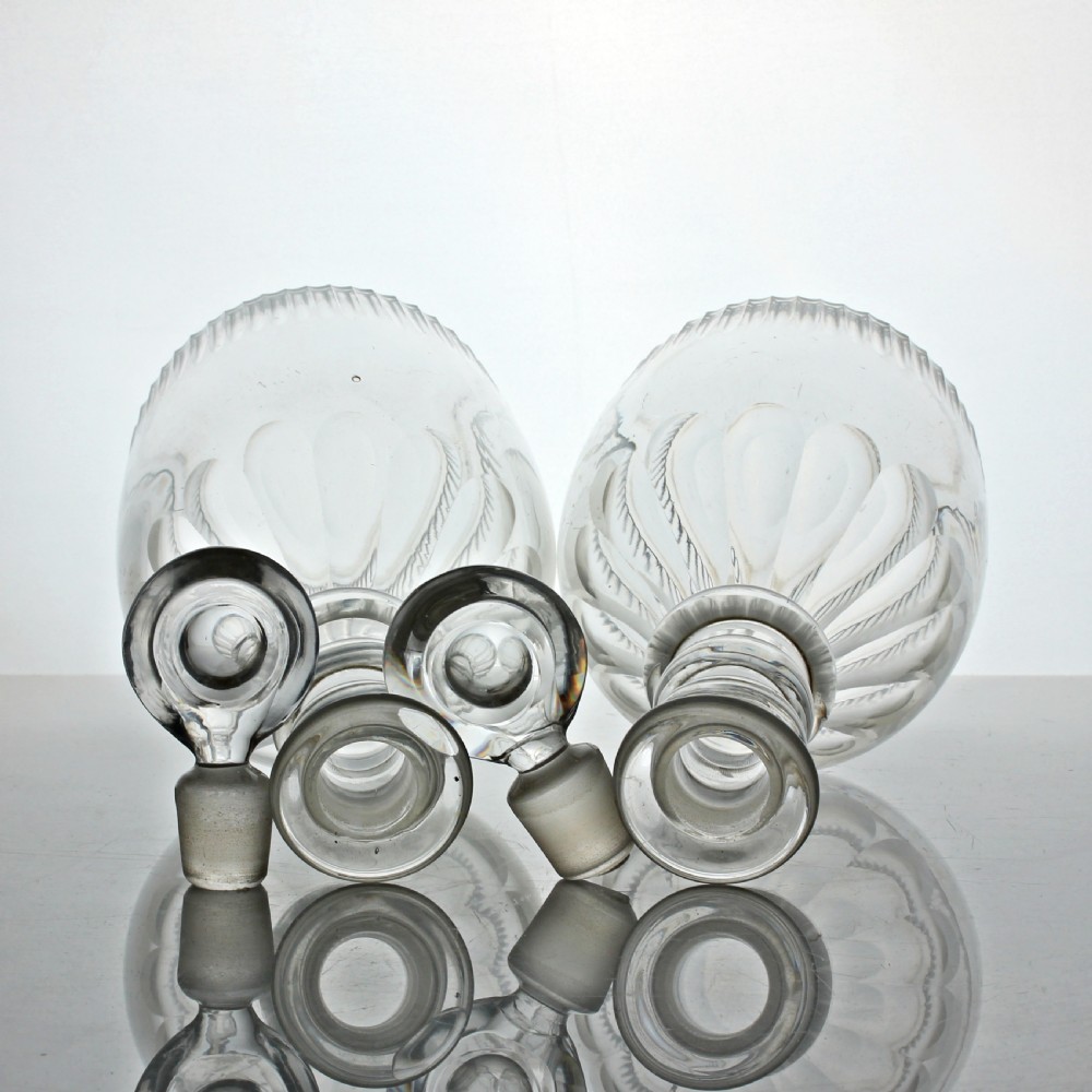A pair of Georgian clear cut-glass decanters featuring three applied neck rings, fluted shoulders, vertical base cuts, and matching target stoppers. View II