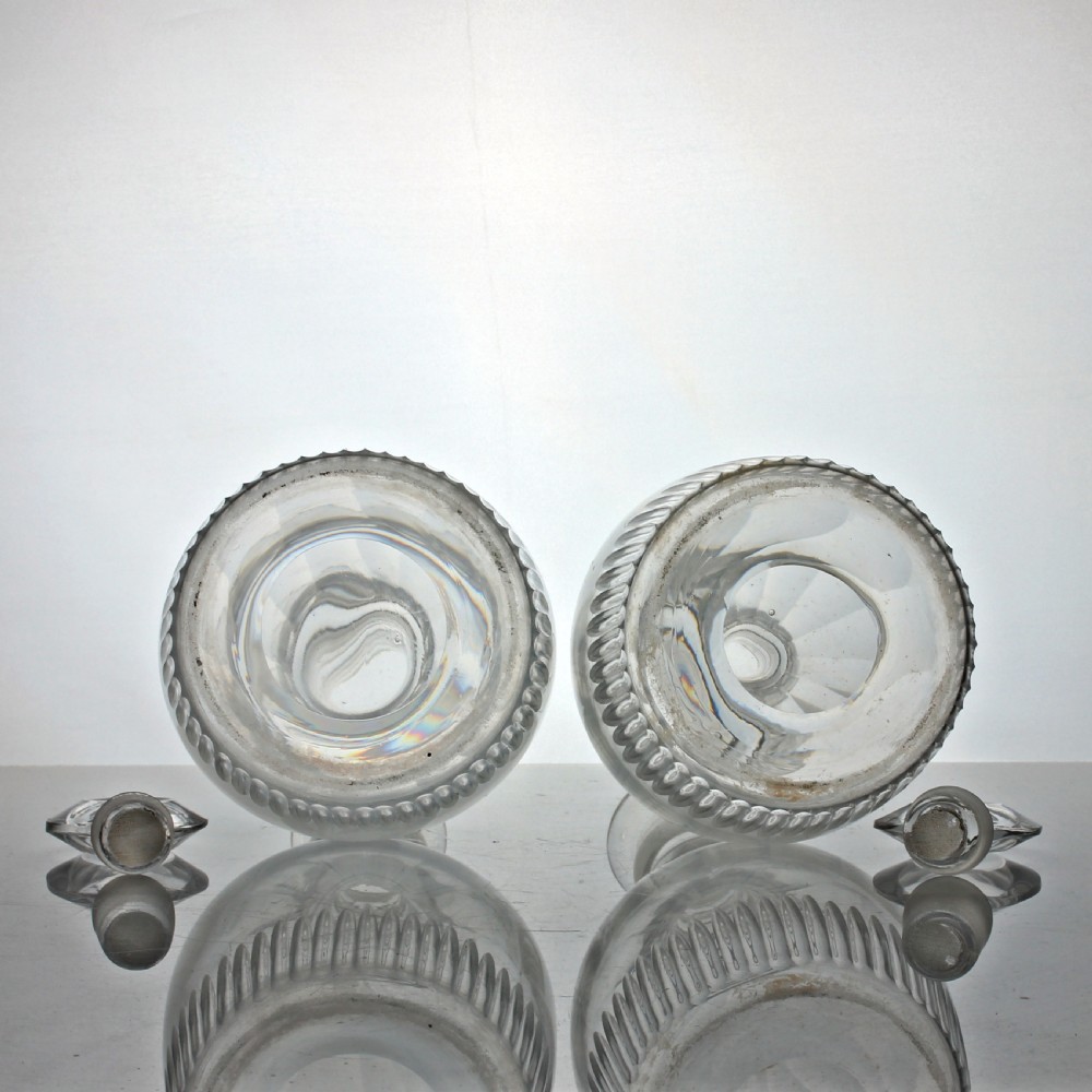 A pair of Georgian clear cut-glass decanters featuring three applied neck rings, fluted shoulders, vertical base cuts, and matching target stoppers. View III