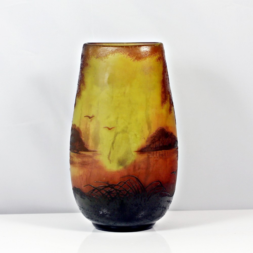 An Art Nouveau cameo glass vase featuring an acid-etched sunset landscape scene with trees, water, and birds in shades of amber, yellow, and dark brown. View III