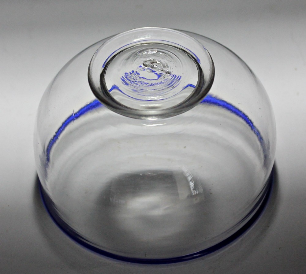 A clear hand-blown glass bowl featuring a dark cobalt blue rim and a short circular footed base. View III