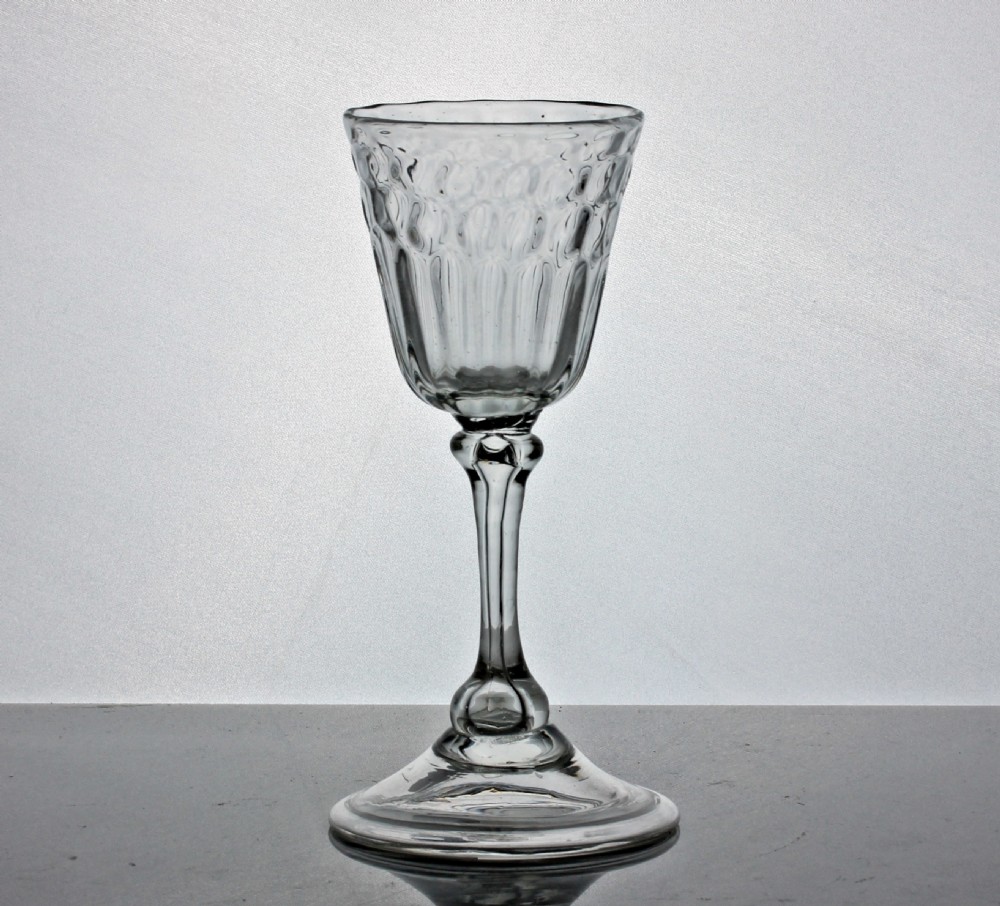 An 18th-century clear glass wine goblet featuring honeycomb moulding on the bowl, a knopped stem, and a broad conical foot.