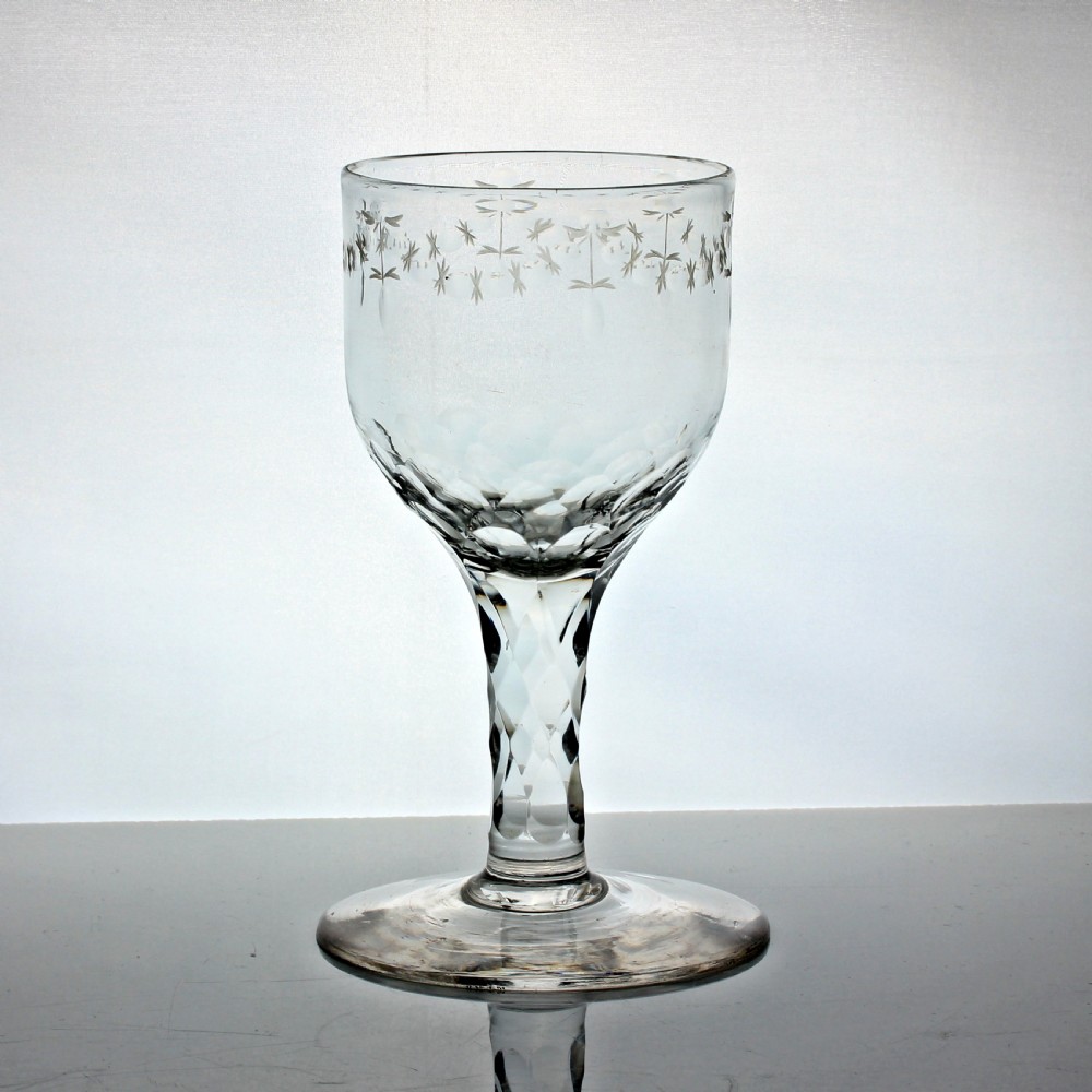 A clear Georgian lead glass wine goblet featuring an engraved rim border, a round funnel bowl, diamond facet-cut stem, and a flat conical foot.