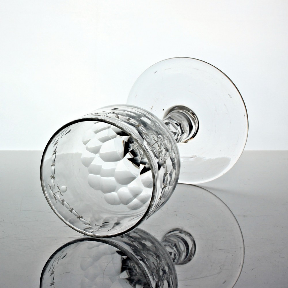 A clear Georgian lead glass wine goblet featuring an engraved rim border, a round funnel bowl, diamond facet-cut stem, and a flat conical foot. View II