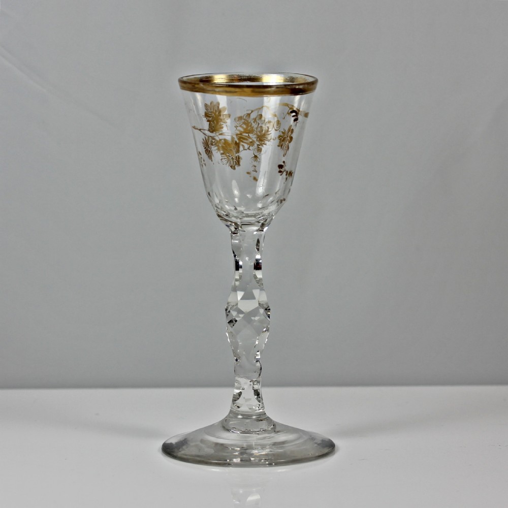 An 18th-century clear lead glass wine glass featuring a gilded vine leaf motif on the bowl and a geometric facet cut stem. View III