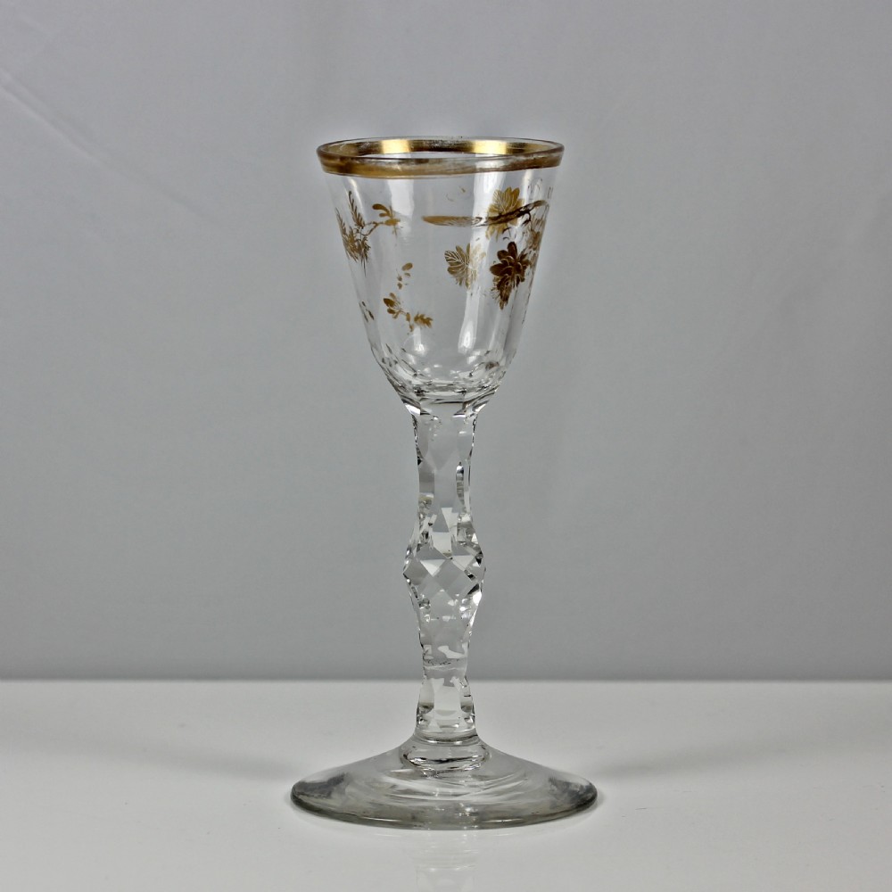An 18th-century clear lead glass wine glass featuring a gilded vine leaf motif on the bowl and a geometric facet cut stem. View IV