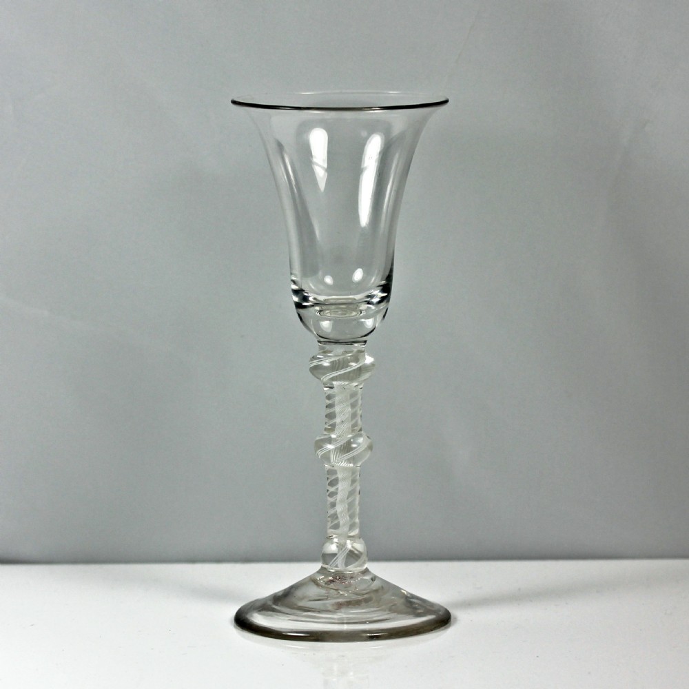 A Georgian clear glass wine goblet featuring a flared bell bowl and a triple-knopped stem with an internal white opaque twist pattern.