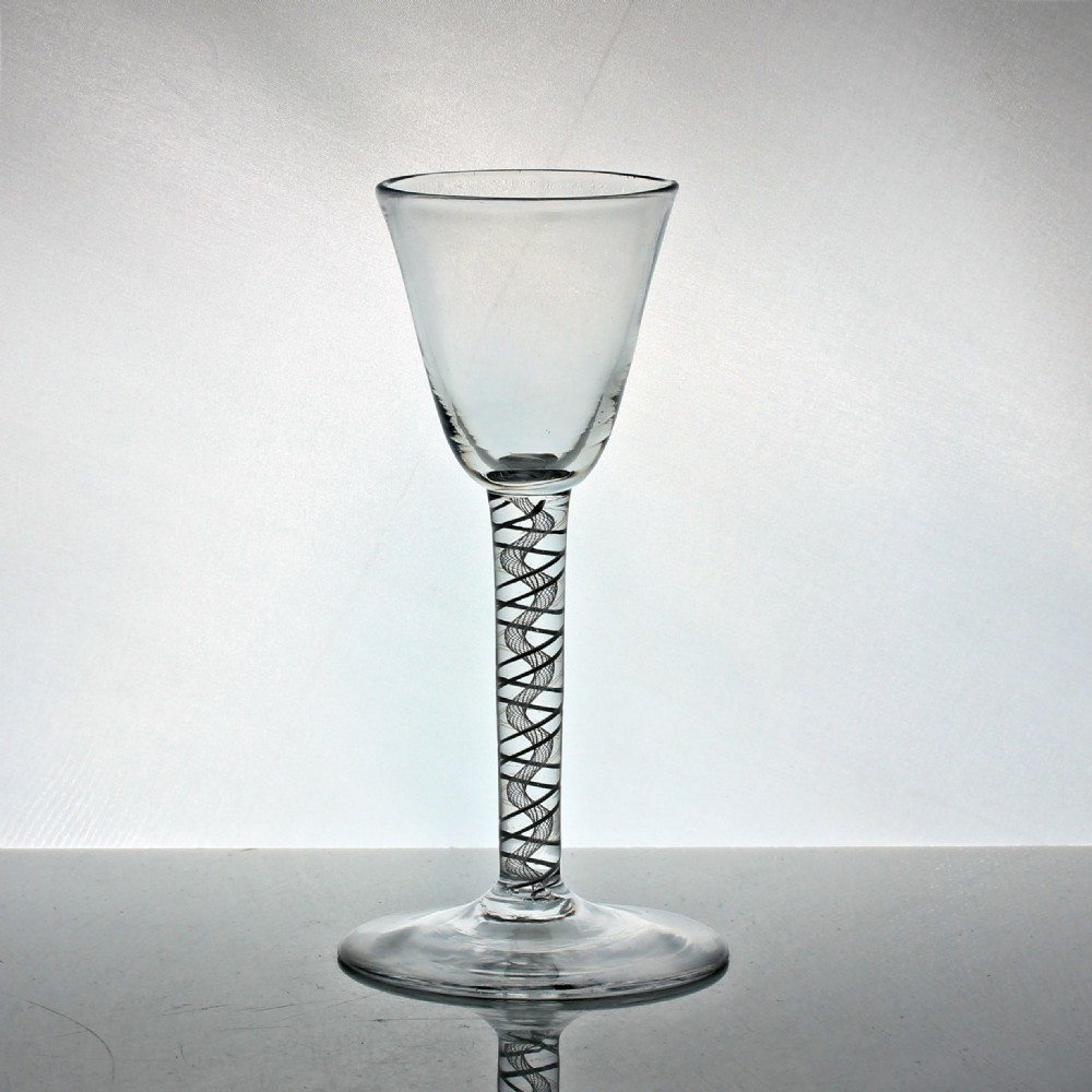 An 18th-century clear glass wine glass featuring a bell-shaped bowl, a straight stem with an internal white double series opaque twist spiral motif, and a conical circular foot. View II