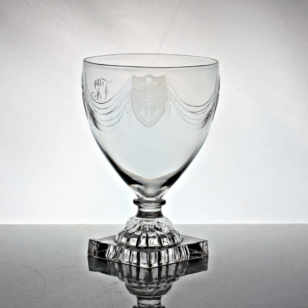 An antique Georgian clear glass rummer featuring an engraved ovoid bowl with swags and shield motifs resting on a square lemon squeezer base. View II