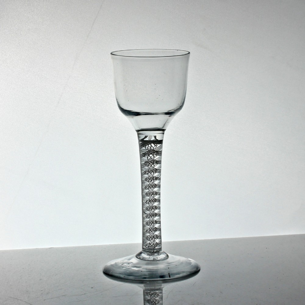 A clear Georgian lead glass wine glass featuring an opaque white double series twist stem and a flared bowl on a circular conical foot.