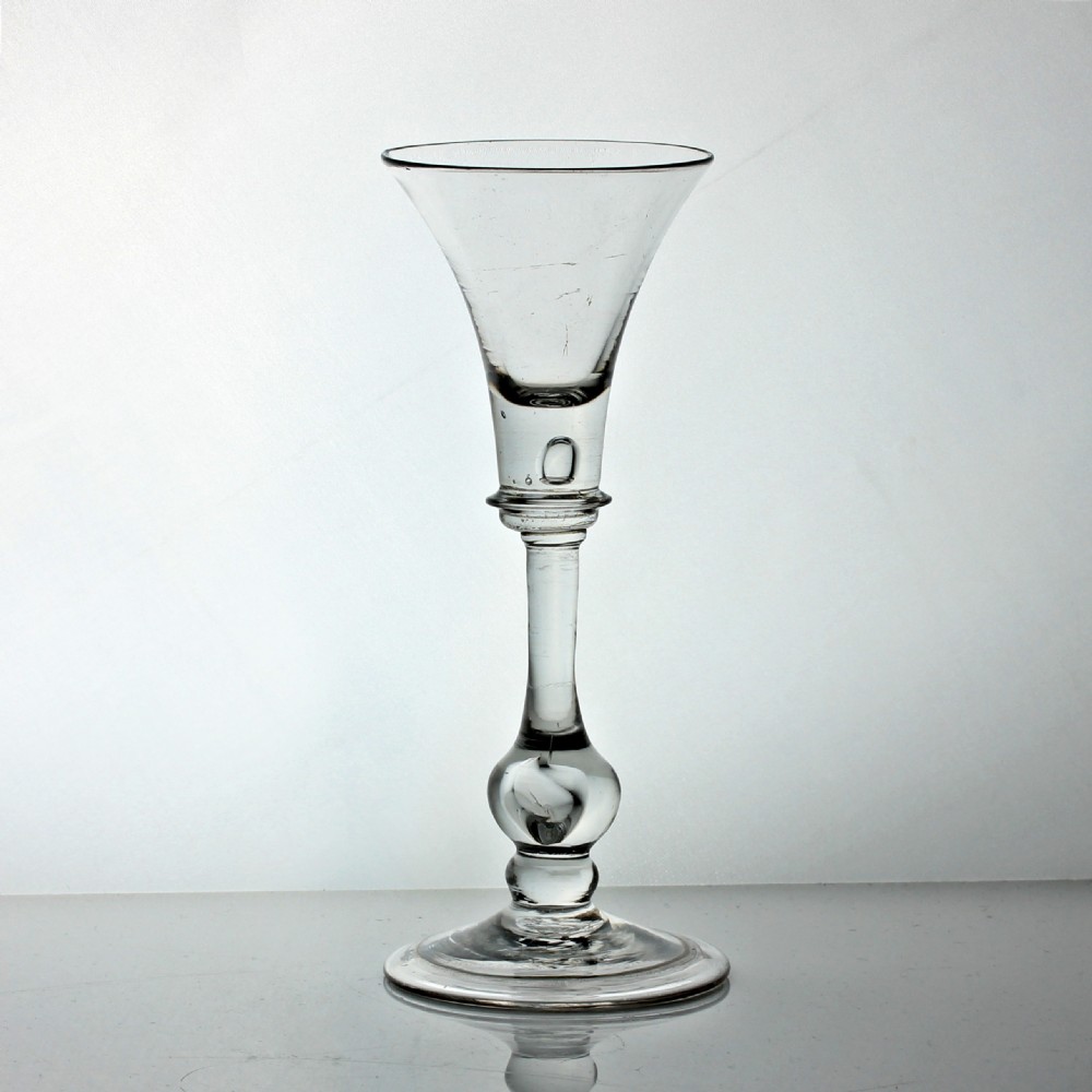 A clear Georgian hand-blown wine glass featuring a flared bell-shaped bowl, a knopped stem with an enclosed air tear, and a circular folded foot.
