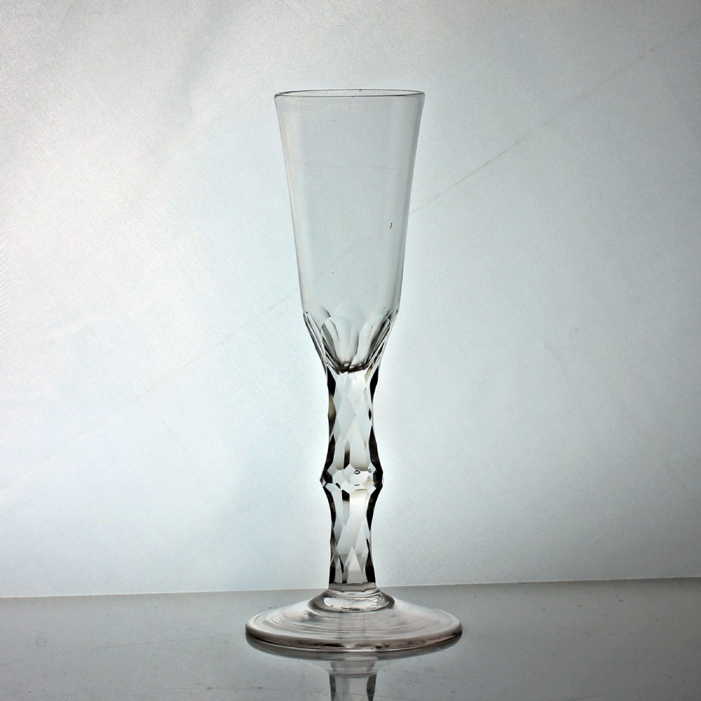 A tall Georgian clear glass featuring a slender conical bowl, a diamond facet cut stem, and a broad circular foot.