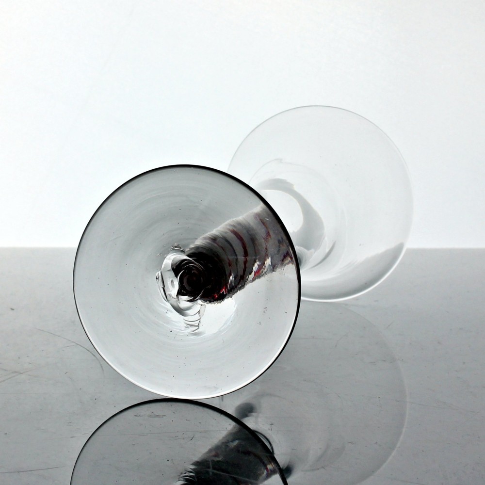 A hand-blown clear glass wine goblet featuring a flared bowl and a stem containing a red and white spiral twist above a circular flat base. View III