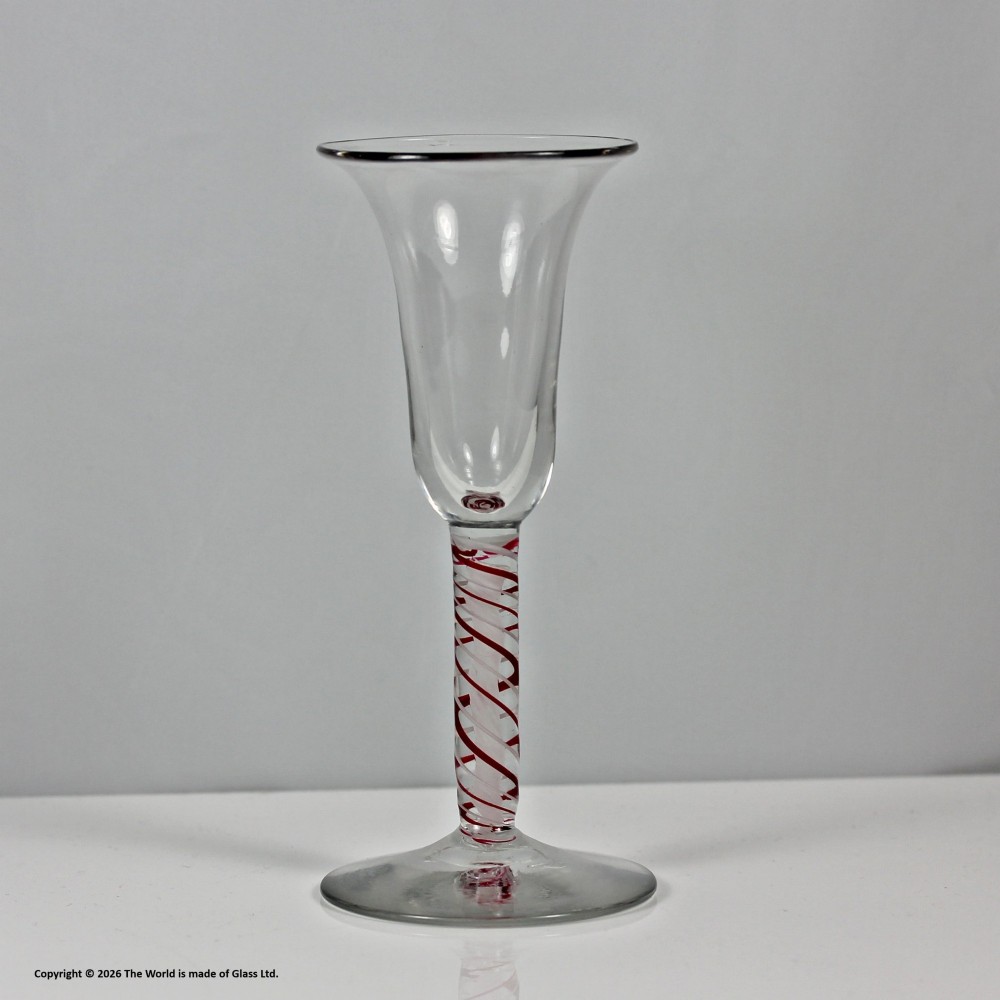 A hand-blown clear glass wine goblet featuring a flared bowl and a stem containing a red and white spiral twist above a circular flat base. View IV