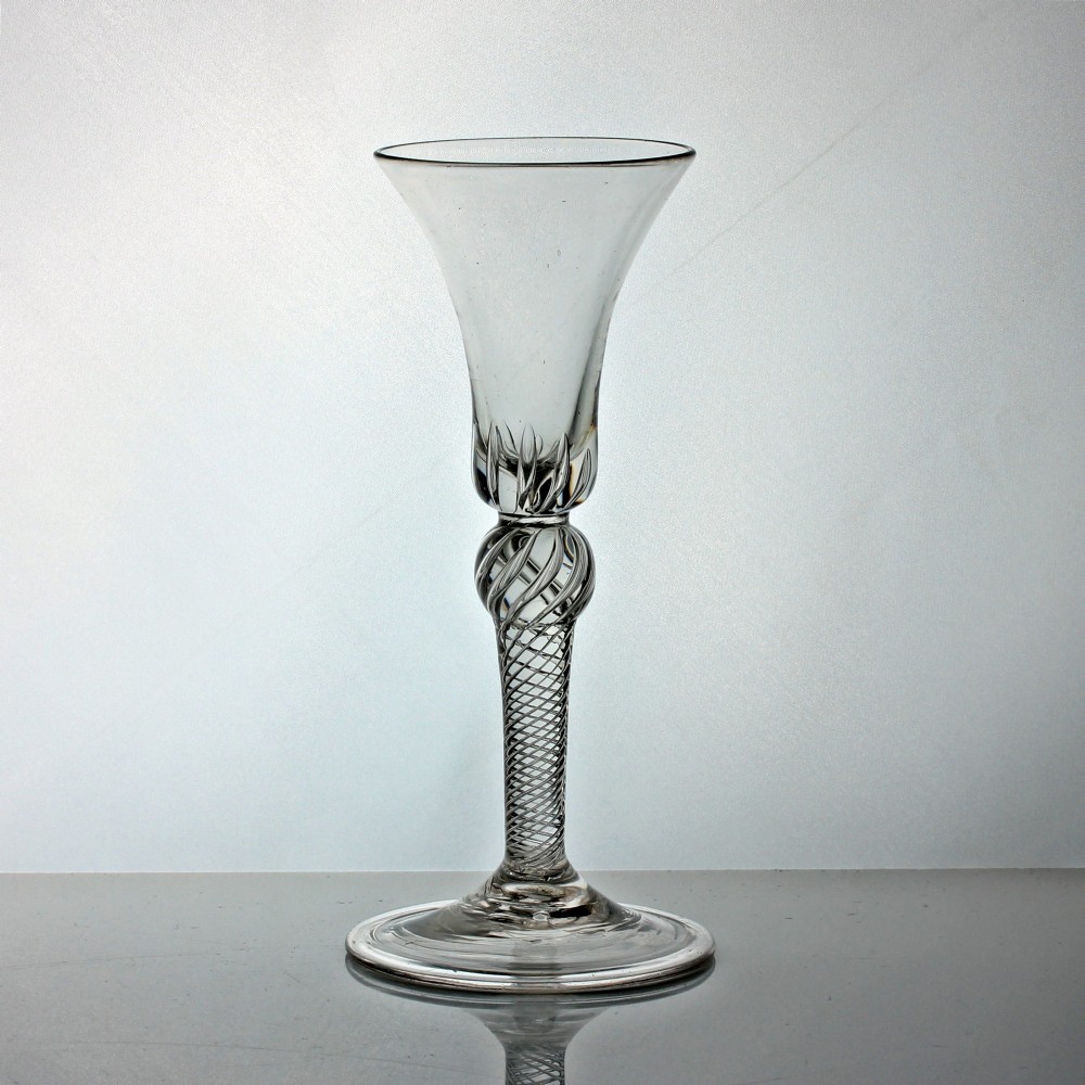 A clear Georgian lead glass wine goblet with a flared bell bowl, a multi-spiral air twist stem featuring a shoulder knop, and a conical folded foot.