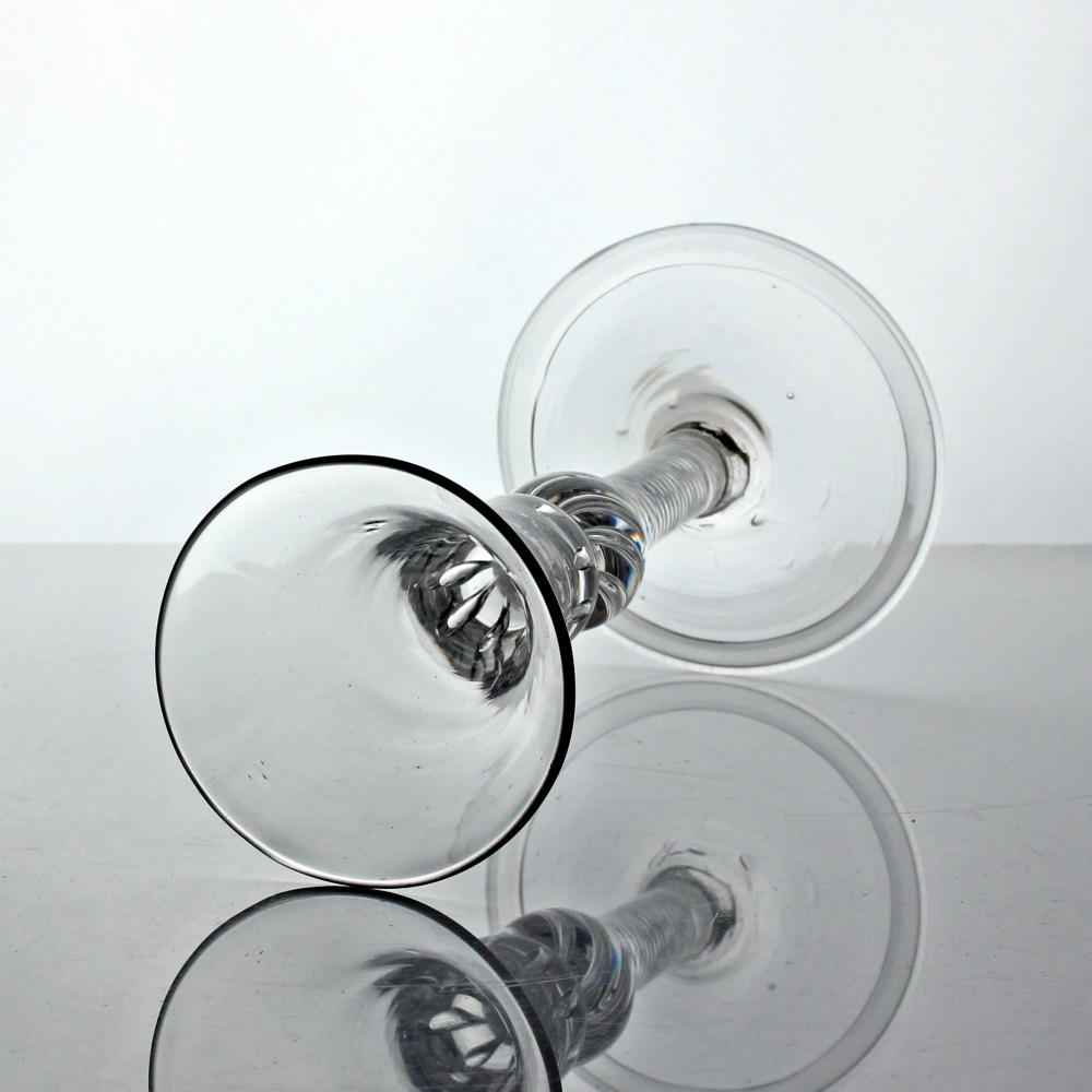 A clear Georgian lead glass wine goblet with a flared bell bowl, a multi-spiral air twist stem featuring a shoulder knop, and a conical folded foot. View II