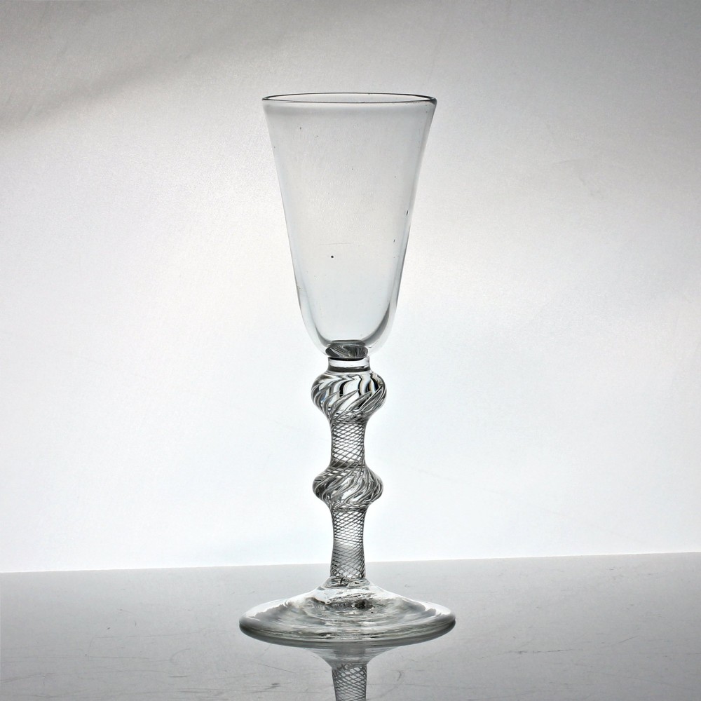 A tall clear glass featuring a conical bowl, a multi-spiral air twist stem with knops, and a circular flat foot.