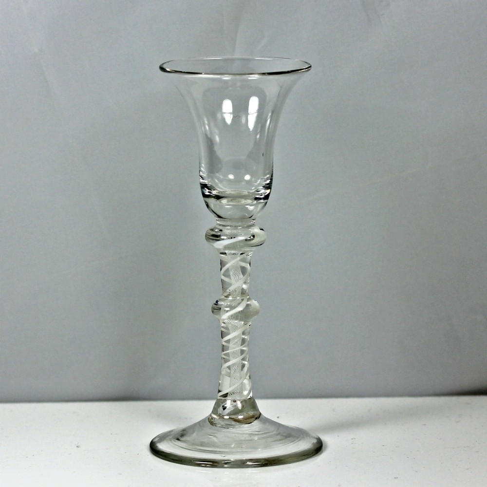 A Georgian clear glass wine glass featuring a bell bowl, a double-knapped stem with internal white opaque twist spirals, and a conical foot.