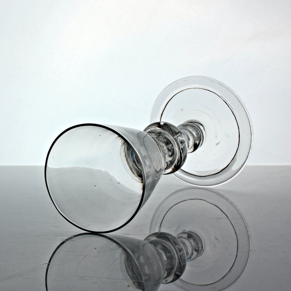 An antique clear glass wine goblet featuring a conical bowl, a stem with a triple annular knop containing an air bubble tear, resting on a wide circular foot. View II