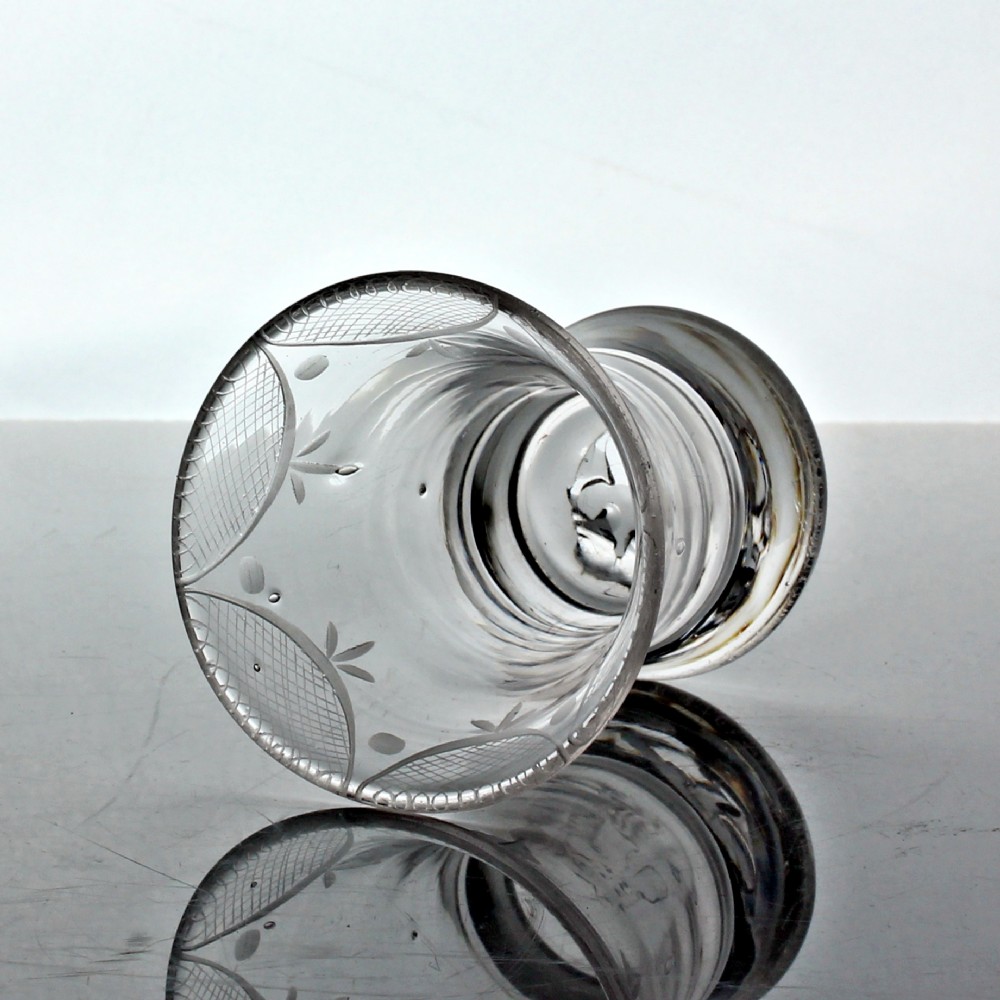 A small clear Georgian firing glass featuring a flared rim, heavy circular base, and wheel-engraved swag and tail decoration. View II