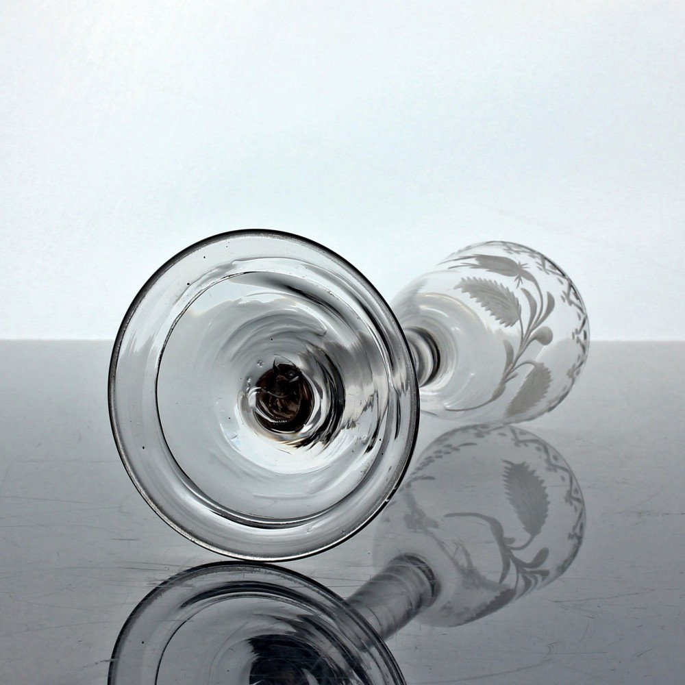 An 18th-century Georgian clear lead glass wine glass featuring a plain stem, circular base, and wheel-engraved floral motif on the bowl. View V