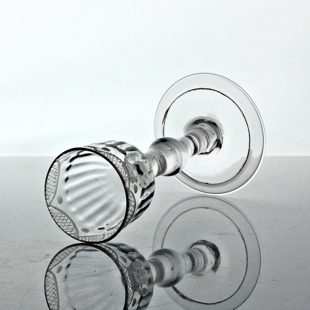 An 18th-century clear lead glass wine goblet featuring a swag and tail engraved rim, a knopped balustroid stem, and a flat circular foot. View II