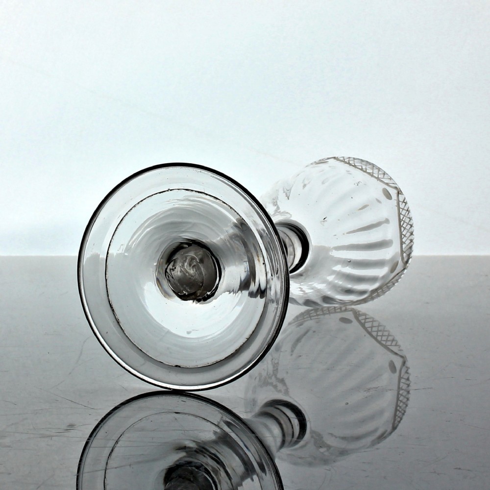 An 18th-century clear lead glass wine goblet featuring a swag and tail engraved rim, a knopped balustroid stem, and a flat circular foot. View III