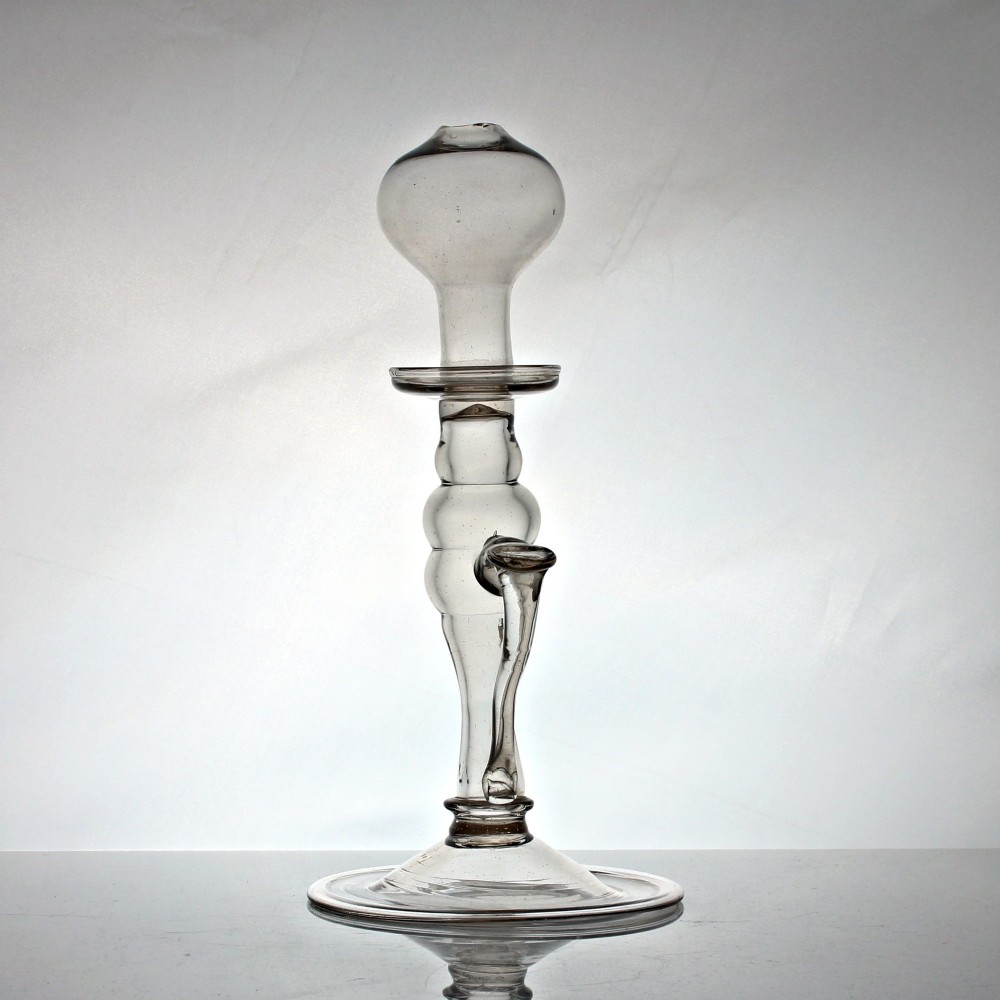 A tall Georgian hand-blown clear glass oil lamp featuring a bulbous top reservoir, a knopped central stem with an applied loop handle, and a wide circular foot. View II