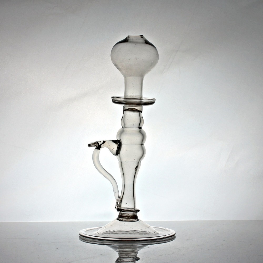 A tall Georgian hand-blown clear glass oil lamp featuring a bulbous top reservoir, a knopped central stem with an applied loop handle, and a wide circular foot. View III