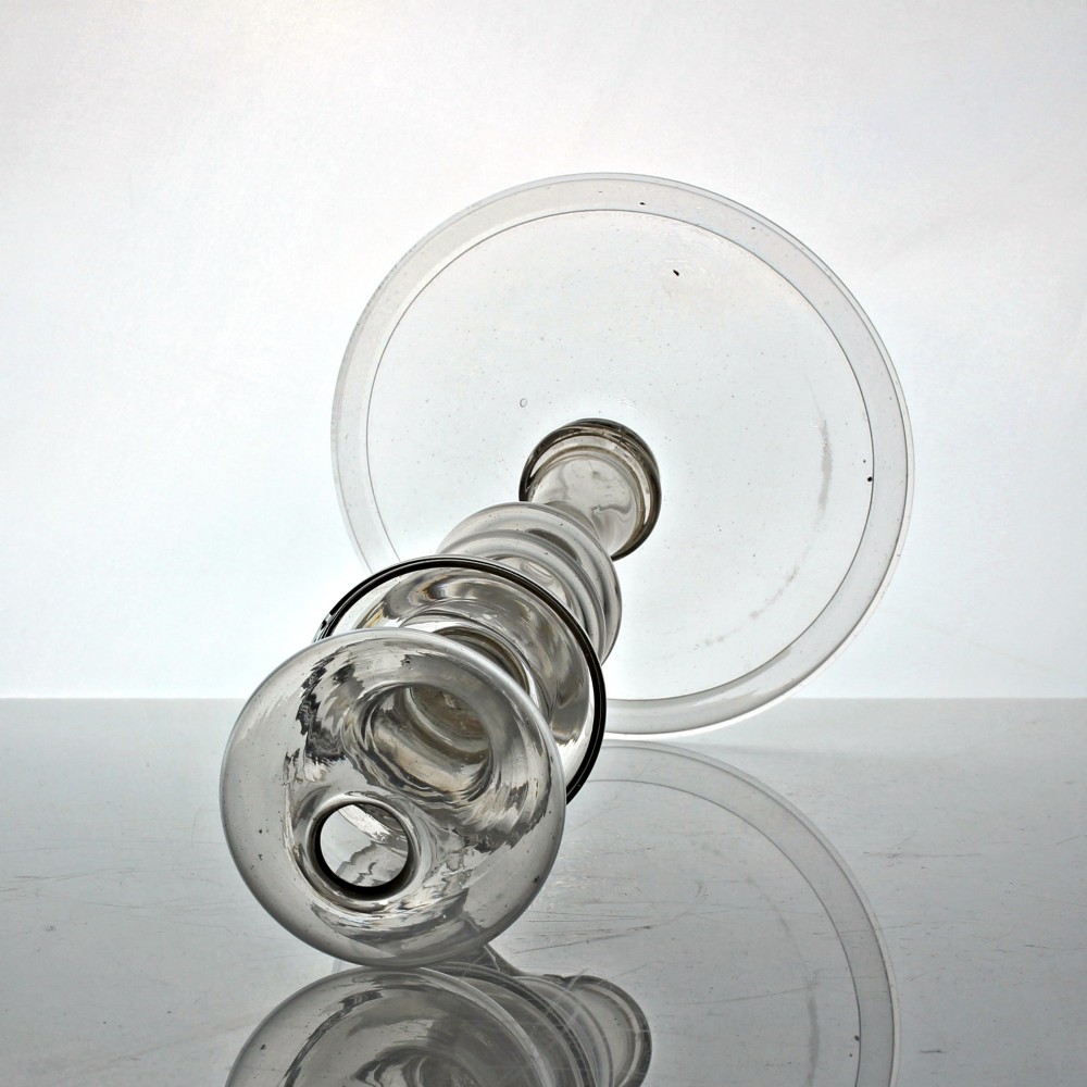 A tall Georgian hand-blown clear glass oil lamp featuring a bulbous top reservoir, a knopped central stem with an applied loop handle, and a wide circular foot. View IV