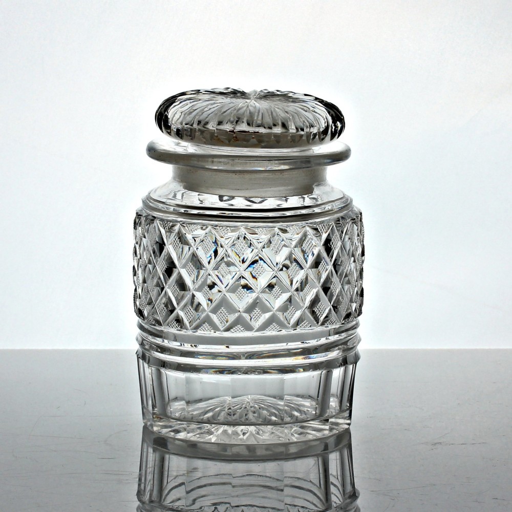 A clear Georgian cut glass cylindrical pickle jar featuring strawberry diamond cutting and a matching fitted glass lid.