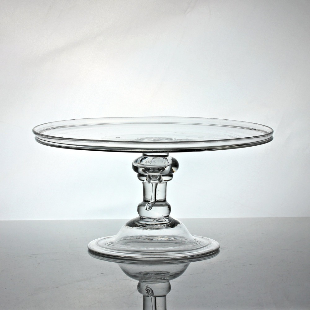 A clear Georgian glass tazza featuring a flat circular tray top supported by a central baluster stem with an internal tear air bubble and a wide conical foot.