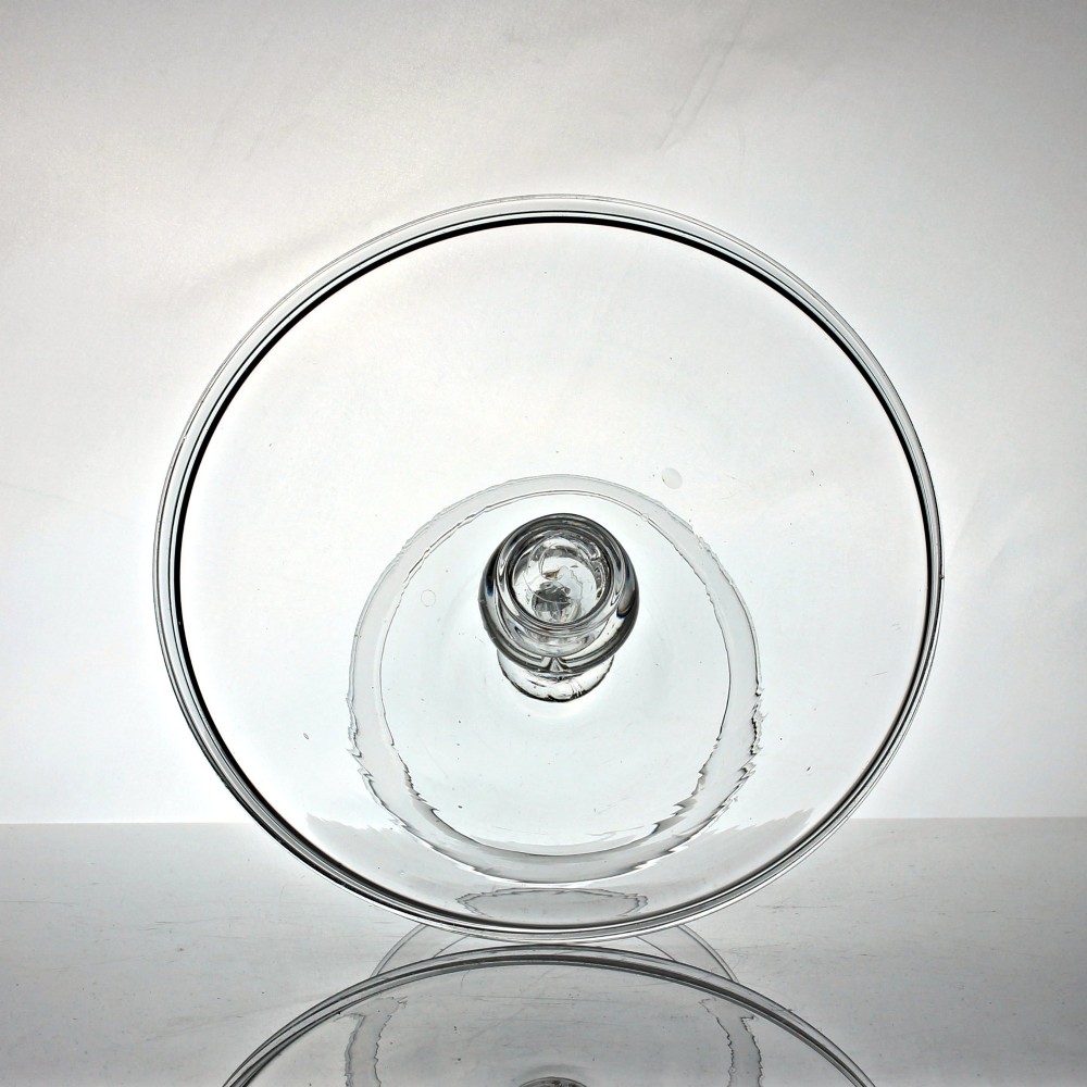 A clear Georgian glass tazza featuring a flat circular tray top supported by a central baluster stem with an internal tear air bubble and a wide conical foot. View II