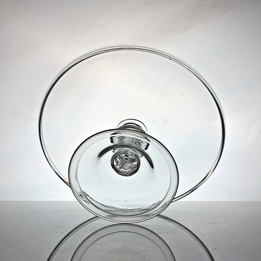 A clear Georgian glass tazza featuring a flat circular tray top supported by a central baluster stem with an internal tear air bubble and a wide conical foot. View III