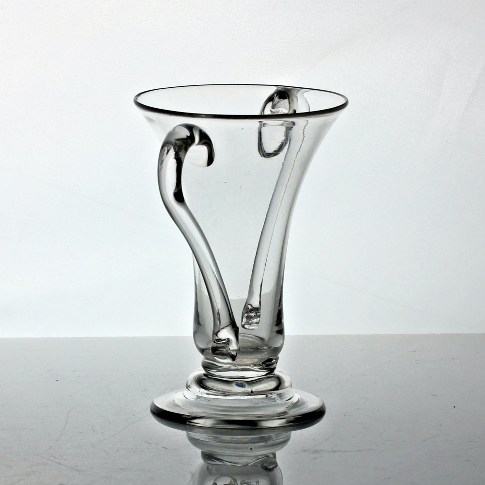 A clear Georgian hand-blown glass cup featuring two curved side handles, a flared rim, and a thick pedestal base. View III