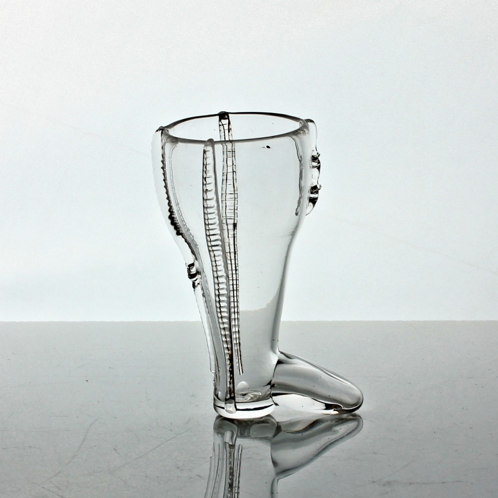 A clear hand-blown Georgian glass vessel modelled in the shape of a boot with vertical rigaree decoration.