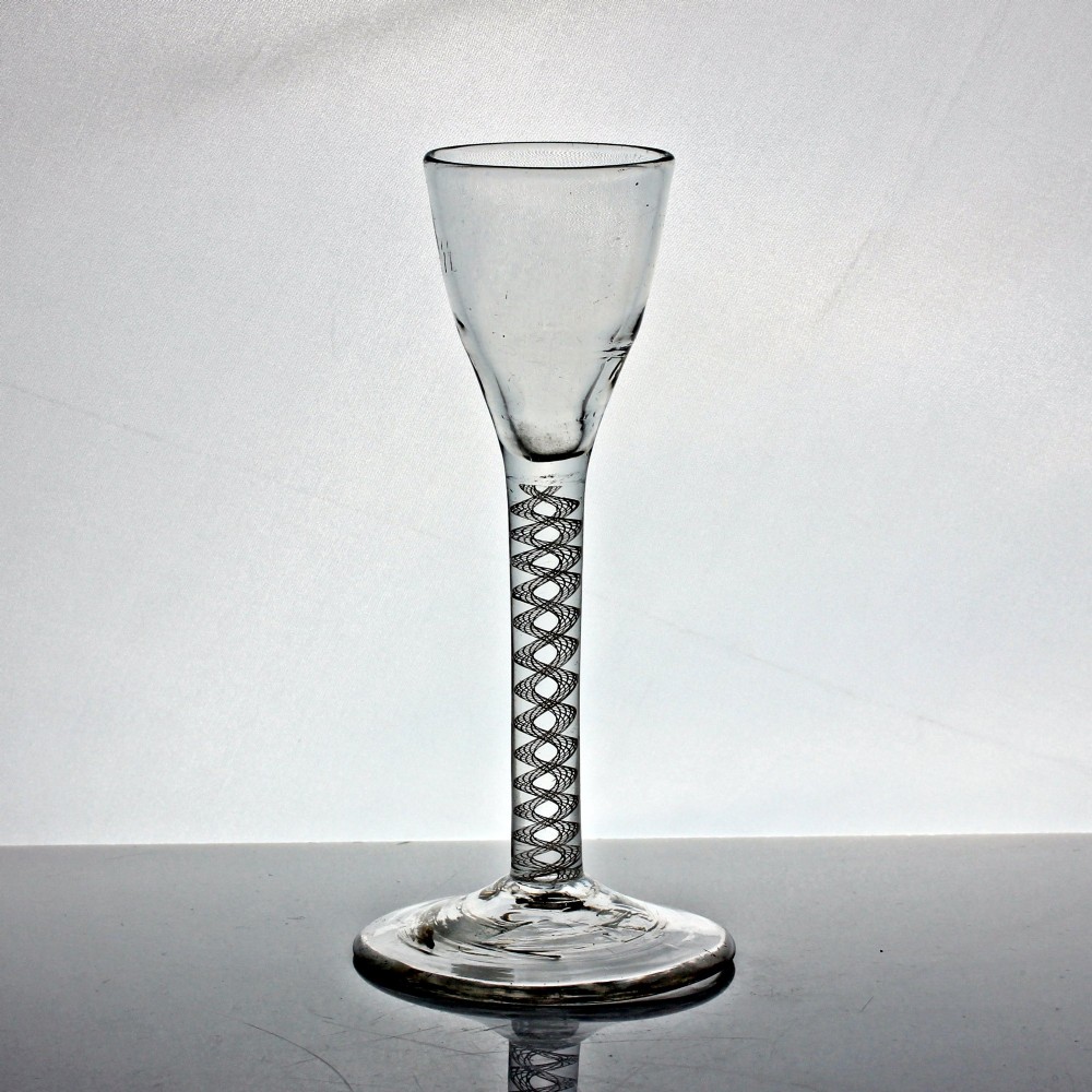 An antique clear glass wine glass featuring a bell-shaped bowl, an internal white opaque twist stem, and a flat conical base. View II