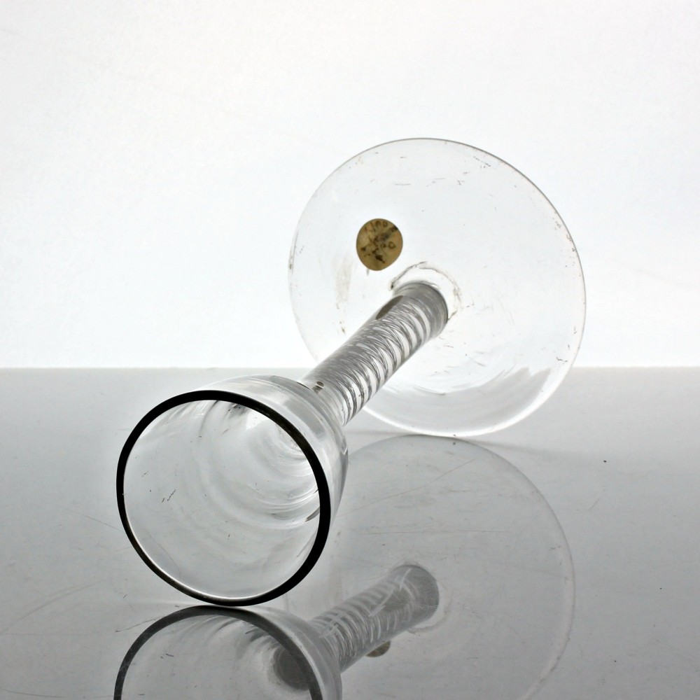 An antique clear glass wine glass featuring a bell-shaped bowl, an internal white opaque twist stem, and a flat conical base. View III