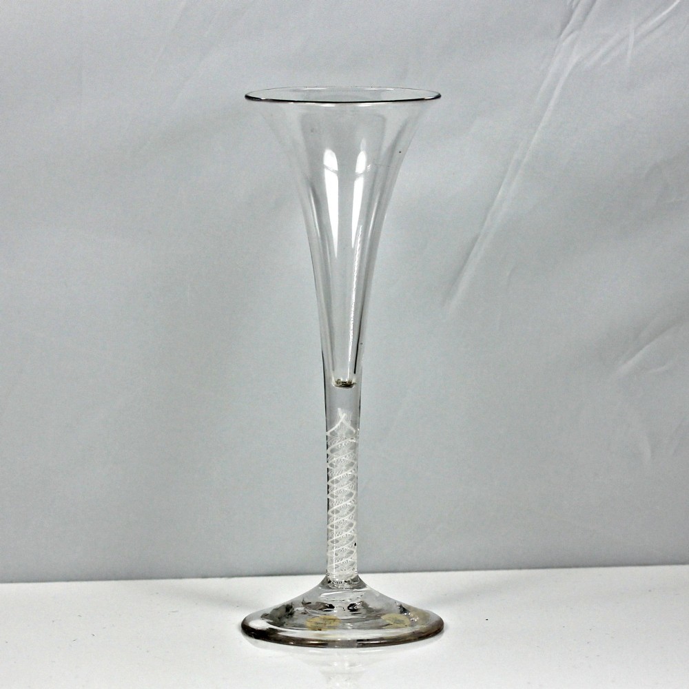 An 18th-century clear glass wine glass featuring a tall trumpet-shaped bowl, a double series opaque twist stem, and a wide conical foot.